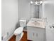 A half bathroom with a white vanity, light fixtures, and a hardwood floor at 1935 Wenton Pl, Lawrenceville, GA 30044