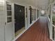 Covered front porch with black door, sidelight windows, and wood flooring at 1935 Wenton Pl, Lawrenceville, GA 30044