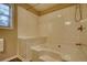 Clean bathroom featuring a tiled bathtub with a shower, a bench, and neutral-colored walls at 2194 Highway 20 E., Mcdonough, GA 30252