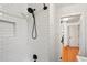 White tiled shower with dark fixtures and a view to a hallway with wooden floors at 1322 Elmhurst Circle Se Cir, Atlanta, GA 30316