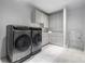 Well-lit laundry room featuring modern front-load washer and dryer, with ample white cabinetry for storage at 3117 W Roxboro Ne Rd, Atlanta, GA 30324