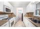 Galley kitchen features white cabinets and appliances, and neutral countertops at 4446 Frontier Way, Sugar Hill, GA 30518