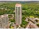 An aerial shot of a modern high-rise apartment building nestled amongst lush green trees and a clear blue sky at 750 Park Ne Ave # 14Se, Atlanta, GA 30326