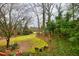 View of an expansive backyard with mature trees, lush ground cover and an outdoor seating area at 192 Maple Wood Dr, Lawrenceville, GA 30046