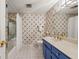 Tiled bathroom with a modern vanity, bright blue cabinetry, and a shower-tub combination featuring patterned wallpaper at 192 Maple Wood Dr, Lawrenceville, GA 30046