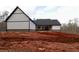 Backyard view of a white farmhouse with black trim and an unfinished yard at 472 Price Rd, Carrollton, GA 30116