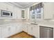 Well-lit kitchen with white cabinets, hardwood floors, stainless steel appliances, and a neutral-toned backsplash at 11180 West Rd, Roswell, GA 30075