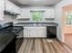 Bright kitchen with white cabinets, stainless steel sink, black appliances, and wood floor at 3783 Red Rose Ct, Loganville, GA 30052