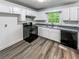 Well-lit kitchen features white cabinets, black appliances and wood flooring at 3783 Red Rose Ct, Loganville, GA 30052