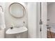 Clean bathroom with a pedestal sink, round mirror, and neutral decor at 201 16Th Nw St # 4, Atlanta, GA 30363