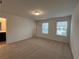An empty bedroom featuring two windows for natural light and neutral carpet at 2105 Stillhaven Pl, Douglasville, GA 30135