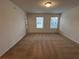 An empty bedroom with neutral carpet and two windows for natural light at 2105 Stillhaven Pl, Douglasville, GA 30135