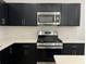 Close up of the kitchen with dark cabinetry, stainless steel appliances, and subway tile backsplash at 2105 Stillhaven Pl, Douglasville, GA 30135