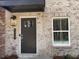 Close-up of a brick home's front door with a glass pane, sidelight, and modern house number at 5459 Blossomwood Sw Trl, Mableton, GA 30126