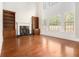Bright living room with tall windows, a fireplace with built-in shelving, and gleaming hardwood floors at 135 Waterlace Way, Fayetteville, GA 30215