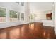 Open-concept space featuring hardwood floors, large windows, and a glimpse into the kitchen area at 135 Waterlace Way, Fayetteville, GA 30215
