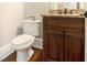 A powder room with a wood vanity, granite countertop and bronze fixtures at 135 Waterlace Way, Fayetteville, GA 30215