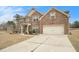 Charming two-story brick home featuring a manicured lawn and attached two-car garage at 10 Tabor Trce, Oxford, GA 30054