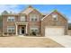 Charming two-story brick home featuring a manicured lawn and attached two-car garage at 10 Tabor Trce, Oxford, GA 30054