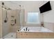 Bathroom featuring a glass shower, a soaking tub, and a window allowing natural light at 829 Waterford Estates Mnr, Canton, GA 30115
