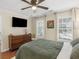 Comfortable bedroom featuring a bed, modern dresser, mounted television, hardwood floors and natural lighting at 144 Wyckliffe Dr, Locust Grove, GA 30248