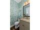 Charming powder room with bright wallpaper, a decorative mirror, and granite countertops offers a stylish, functional space at 122 Brighton Blvd, Woodstock, GA 30188