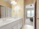 Bathroom with double sinks in white cabinets and warm walls and an open doorway to a bright bedroom at 3162 Abbey Sw Dr, Atlanta, GA 30331
