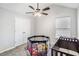 Neutrally painted bedroom with window, ceiling fan, closet and a play area with baby furniture at 4022 Rosebud Park Dr, Snellville, GA 30039