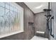 A modern shower with black grab rails, a corner seat, and a designer window at 2705 Luke Edwards Rd, Dacula, GA 30019