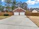 Detached two-car garage made of brick with two white garage doors and long driveaway with wooded background at 2705 Luke Edwards Rd, Dacula, GA 30019