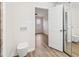 Bright bathroom view showcasing toilet, wood flooring, mirrored wall, and open doorway to another room at 1908 Variations Ne Dr, Atlanta, GA 30329