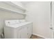 This bright laundry room features a white washer and dryer with open shelving above for storage at 1908 Variations Ne Dr, Atlanta, GA 30329