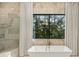 Bright bathroom featuring soaking tub with modern fixtures and large scenic window at 5060 Lake Forrest Dr, Atlanta, GA 30342