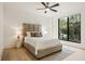 Bedroom with a padded headboard, decorative pillows and a large window view of the trees outside at 5060 Lake Forrest Dr, Atlanta, GA 30342