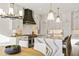 Gourmet kitchen with marble countertops, white cabinets, a black range hood, and modern lighting at 5060 Lake Forrest Dr, Atlanta, GA 30342