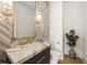 Elegant powder room with unique tile, gold fixtures, and a marble countertop at 5060 Lake Forrest Dr, Atlanta, GA 30342