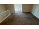 Bright living room with sliding glass doors leading to an outdoor space, carpeted floors and stairs at 533 Fayetteville Rd, Fairburn, GA 30213