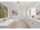 This white bathroom features double sinks, large mirrors, and a freestanding tub under a window at 4895 Lansbury Dr, Atlanta, GA 30342