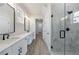 Bathroom featuring double sink vanity, framed mirrors and a glass enclosed shower with black trim at 158 South Village Ave, Holly Springs, GA 30115