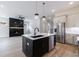 Open kitchen featuring stainless steel appliances, island with dark cabinetry and a view of the fireplace at 158 South Village Ave, Holly Springs, GA 30115
