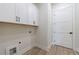 Laundry room features white cabinets for storage over light colored flooring at 158 South Village Ave, Holly Springs, GA 30115
