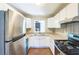 Galley kitchen featuring stainless steel appliances, stone countertops, white cabinets, and wood-look flooring at 5063 White Sw Blvd, Mableton, GA 30126