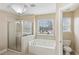 Bright bathroom featuring a glass enclosed shower and soaking tub, with a window view at 114 Highgrove Pl, Mcdonough, GA 30253
