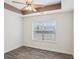 Cozy bedroom with wood-look flooring, a tray ceiling with fan, and a window view at 114 Highgrove Pl, Mcdonough, GA 30253