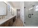 Bathroom with double vanities, a large mirror, and a walk-in shower with glass doors at 160 South Village Ave, Holly Springs, GA 30115