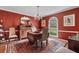 Elegant dining room with a chandelier, dark red walls, hardwood floors, and a window at 1453 Reagan Cir, Conyers, GA 30012