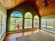Bright living room featuring a wood ceiling, chandelier, hardwood floors, and three large arched windows overlooking the landscaped yard at 1453 Reagan Cir, Conyers, GA 30012