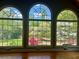 Close up of arched windows overlooking lush backyard with mature trees, bright pink azaleas and a white hammock strung between the trees at 1453 Reagan Cir, Conyers, GA 30012
