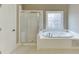 White tiled bathroom showcasing a large soaking tub with a window at 3835 Greenside Ct, Dacula, GA 30019