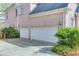 Spacious two-car garage with white doors and a concrete driveway, complemented by green landscaping at 3835 Greenside Ct, Dacula, GA 30019